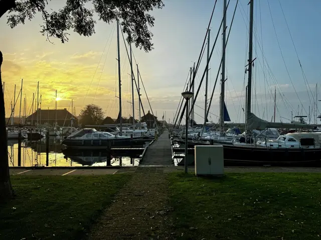 Sonnenuntergang über dem Hafen, Wiese und Steg im Vordergrund