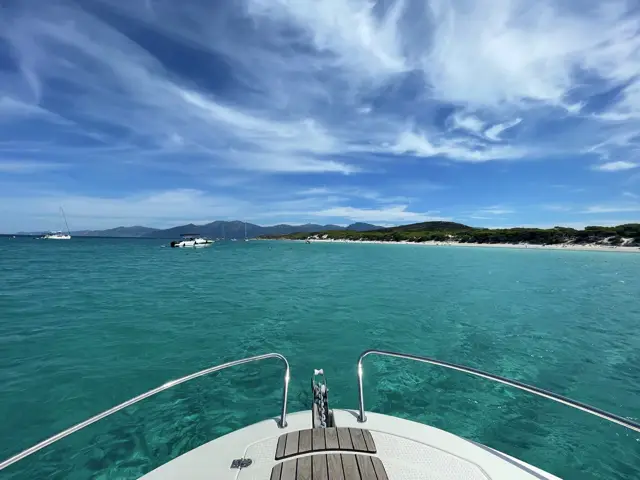 Blick über den Bug auf eine türkise Bucht mit Strand