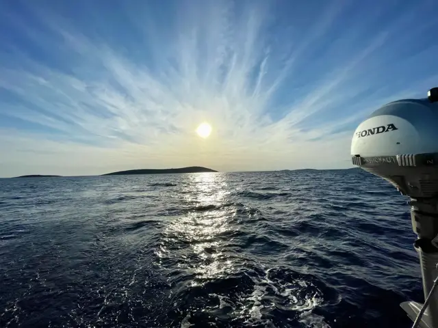 Sonne über dem Meer, am Heck der Außenborder