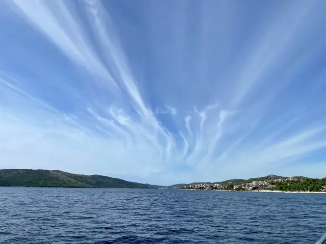 Federwolken über der Küste und tiefblauem Wasser