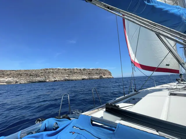 Unter Segeln entlang einer flachen Felsinsel