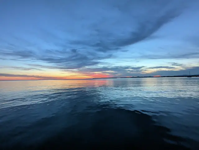 Abendhimmel mit dunklen Wolken über glattem Wasser